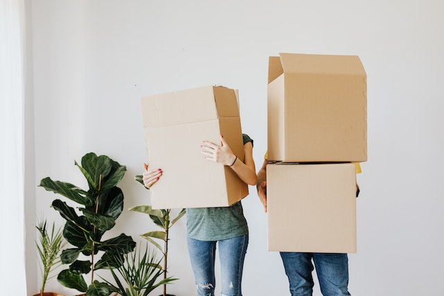 two people holding stacks of boxes